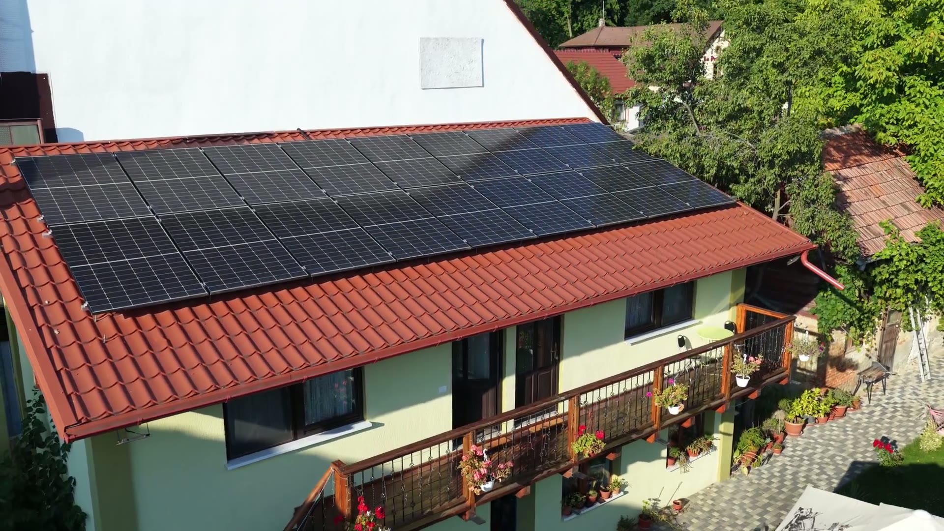 Exteriorul casei, cu balconul de lemn plin de flori