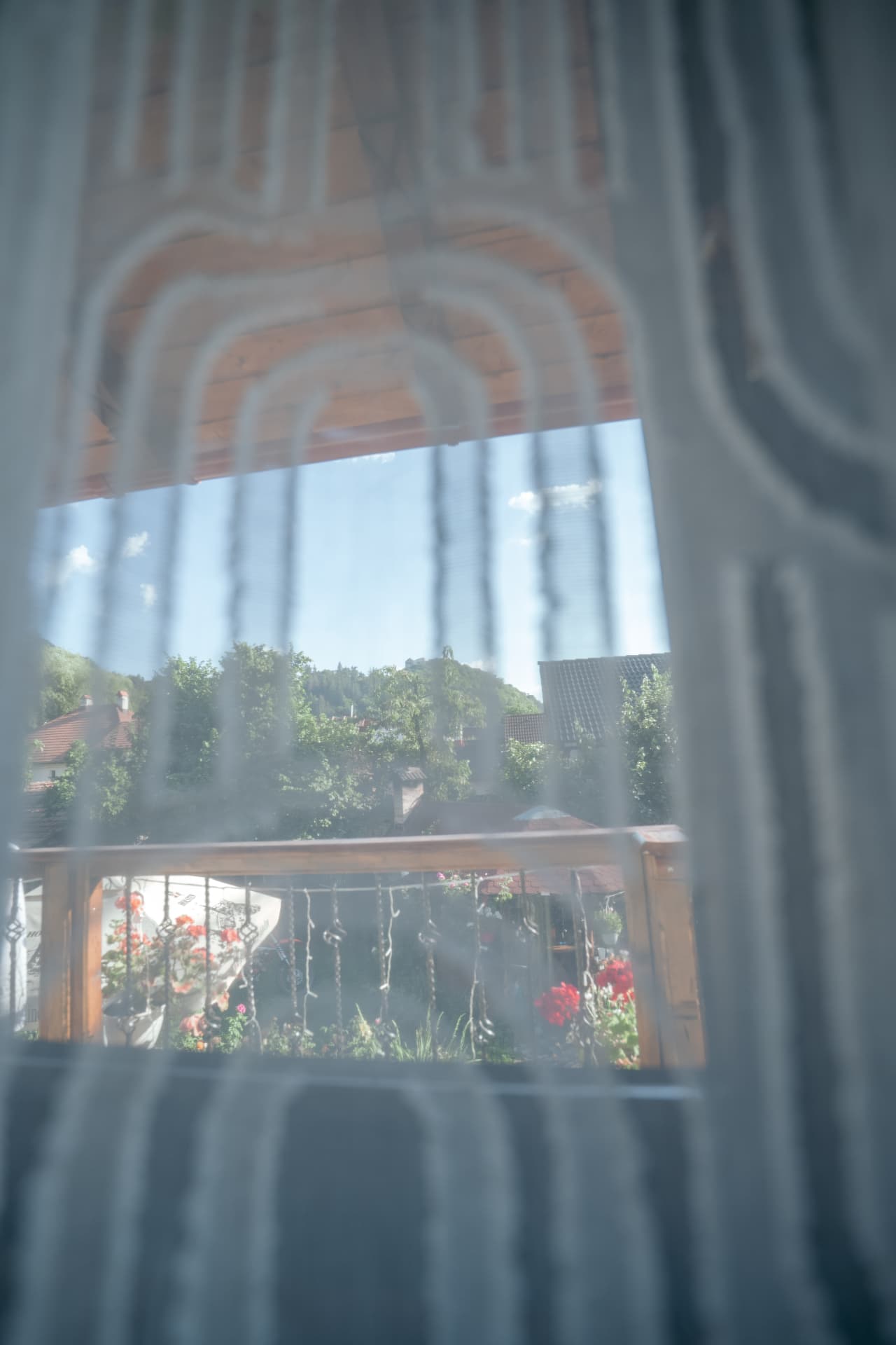 Balconul cu flori și dealul cetății, privite prin perdea